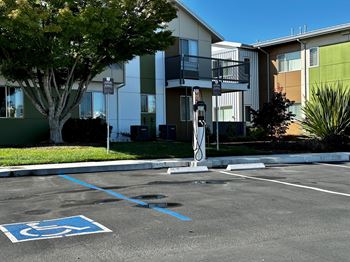 An empty parking lot in front of an apartment building with electrical vehicle charging stations